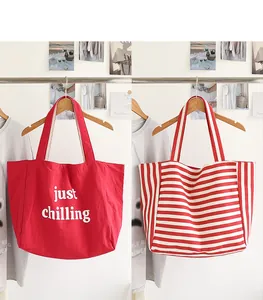 Red tote bag with 'just chilling' text and red striped canvas shoulder bag on a rack