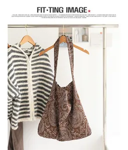 Vue détaillée d'un sac à bandoulière en toile marron avec motif cachemire blanc suspendu sur un portant.