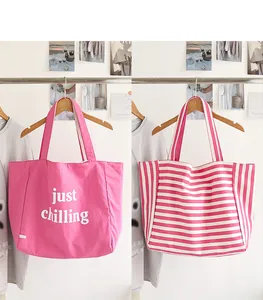 Close-up of pink canvas tote bag featuring solid color with text and striped patterns
