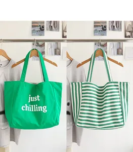 Pair of stylish green and white striped and solid nylon tote bags hanging for display