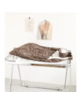 Vue détaillée d'un sac bandoulière en toile paisley marron sur une table transparente