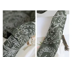 Vue macro de motifs floraux brodés blancs sur un sac à bandoulière en toile vert foncé