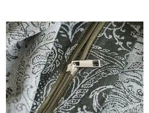 Gros plan sur la fermeture éclair en métal argenté et la broderie florale de ce sac en toile.