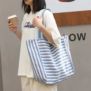 Casual blue and white striped canvas tote bag carried by a model on a grey background