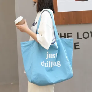 Bolso tote de lona azul claro con estampado just chilling blanco sobre el modelo