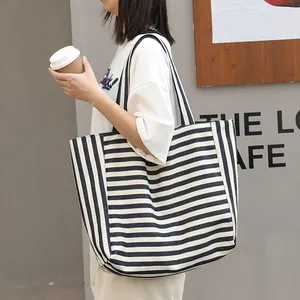 Stylish navy blue and white striped canvas tote bag for women in a casual street setting.