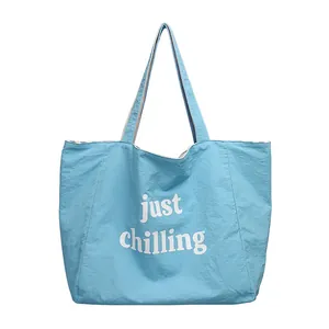Stylish light blue crinkle nylon tote bag featuring white just chilling letter print.