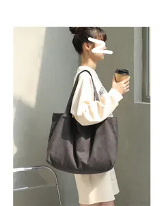 Large capacity solid color canvas tote bag carried by an Asian model in an outdoor setting.