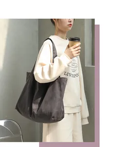 Close-up of large charcoal canvas tote bag carried by model in casual setting