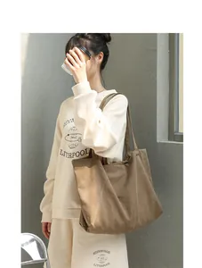 Detail view of a minimalist brown canvas tote bag worn by a model in a lifestyle setting