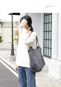 Detalle de un bolso shopping de pana gris con bordado lucido por una modelo