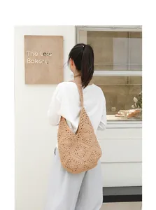 Detailweergave van een handgemaakte beige gehaakte schoudertas gedragen door model.