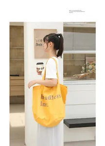 Vista de estilo de vida de un bolso tote de lona amarilla con estampado de letras.