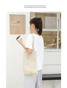 Detailed view of the beige cotton woven mesh beach bag worn over the shoulder
