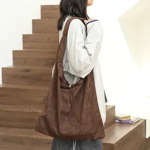Stylish brown suede hobo shoulder bag with drawstring detail shown on a model