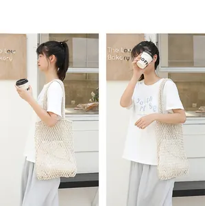 Lifestyle detail of a cream-colored woven mesh beach bag with a drawstring inner pouch
