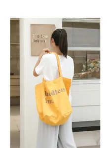 Vista trasera de modelo con un bolso cubo de lona amarilla lavada con logo