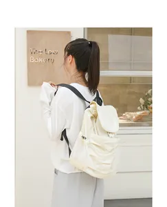 Vista detallada de mochila de nailon crema con diseño plisado usada por una modelo