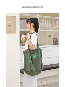 Vista detallada de un gran bolso tote de lona verde militar con estampado de letras al hombro