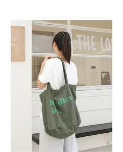 Mujer de espaldas con un bolso tote de lona verde lavado con detalle de letras