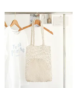 Handmade woven cotton net beach bag with a cream canvas drawstring inner pouch