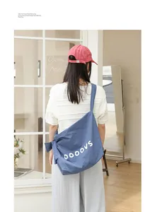 Detailed view of blue nylon crossbody bag with letter print and knot shoulder strap