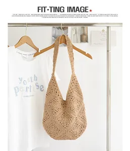Detail van een handgeweven beige katoenen strandtas hangend aan een kledingrek