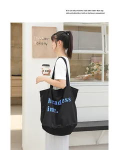 Modelo asiática con bolso tote de lona negra y estampado de letras azules