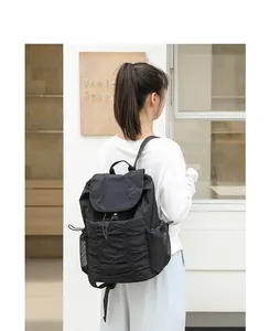 Vista trasera de una mochila de nailon negro plisado en una modelo en entorno urbano