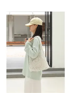 Close-up of stylish cream cotton mesh woven shoulder bag with inner pouch
