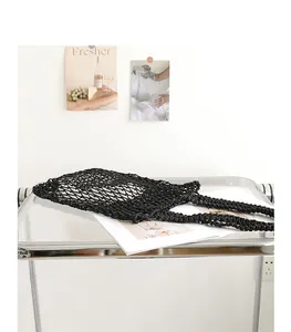 Detail shot of black woven cotton mesh beach bag on a stylish transparent shelf.