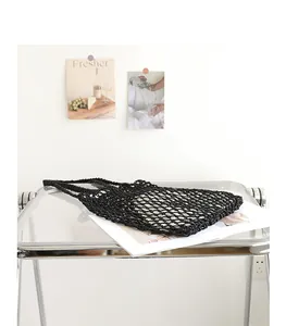 Detailed view of a black woven cotton mesh beach bag displayed on a modern table