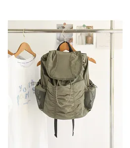 Mochila de nailon plisada verde oliva con bolsillos laterales de malla en un perchero