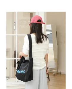 Model wearing a black Japanese style nylon shoulder bag with blue BOYS lettering