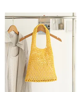 Detailed view of yellow hand-woven cotton mesh bag hanging on a wooden hanger