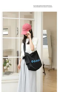 Detailed view of a black nylon crossbody bag featuring blue letters and knot details