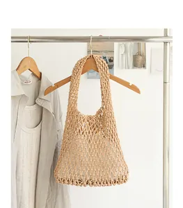 Detail view of a hand-woven cotton mesh shoulder bag hanging on a wooden clothes hanger.