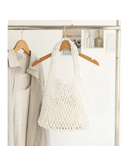 Macro view of white woven cotton mesh underarm bag with drawstring inner pouch