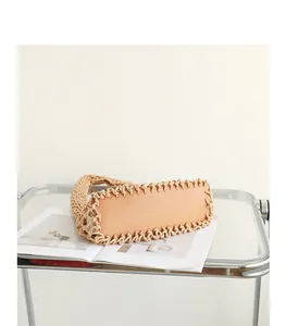 Close-up of the leather bottom and woven cotton mesh of a trendy hollow out armpit bag.