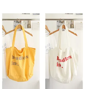Bolsos tote de lona lavada en amarillo y blanco con el detalle impreso 'headless inc.'.