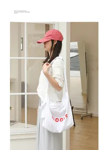 Model wearing a white casual nylon crossbody bag with red letter print and knotted strap.