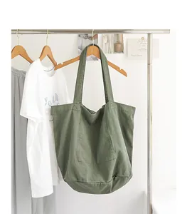 Vista detallada de un bolso tote de lona verde lavado colgado en un soporte