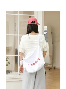 Back view of a woman wearing a white nylon crossbody bag with red letters and knot detail