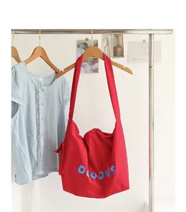 Bright red nylon crossbody bag with blue letters and knotted side pocket detail
