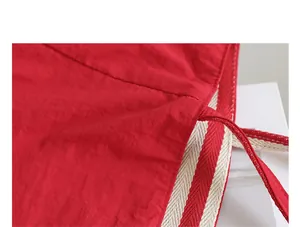 Detalle de cerca de bolso tote de nailon rojo con asa a rayas y textura de logo GG