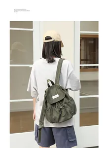 Vista detallada de mochila de lona verde oscuro con cordón y solapa