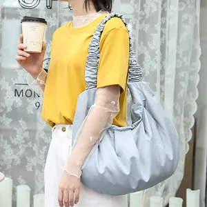 Vista de estilo de vida de un elegante bolso de hombro de nailon plisado azul claro con modelo