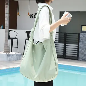 Vista detallada de un elegante bolso hobo de lona informal verde menta junto a la piscina.