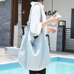 Bolso de lona azul claro de estilo casual en una modelo en un café junto a la piscina
