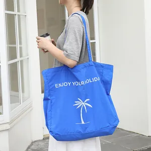 Blaue Nylon-Einkaufstasche mit dem Aufdruck 'ENJOY YOUR HOLIDAY' und weißer Palme.